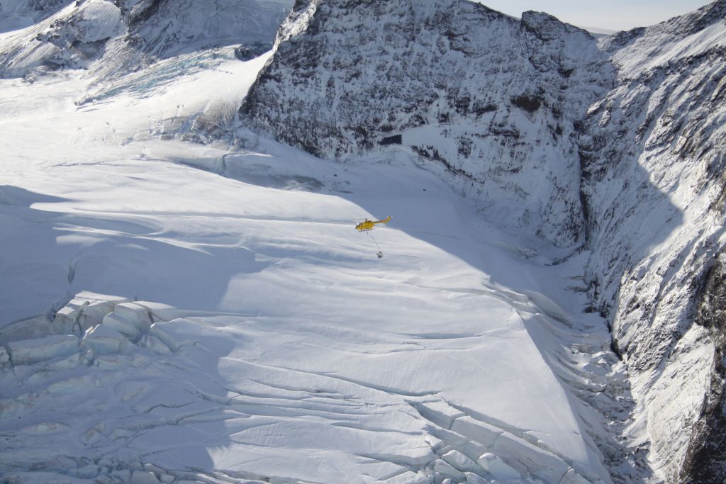 Helicopter transporting rat bait across the frozen mountains on South Georgia Island.