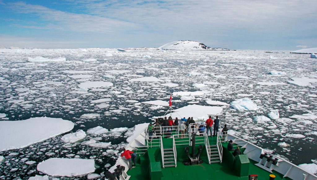 Passengers on the outside deck of an expedition ship watching the horizon